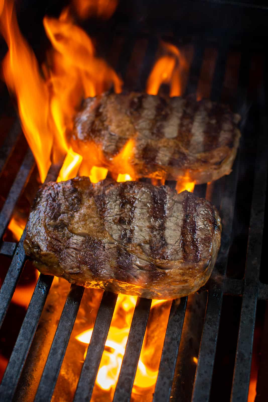 steak being grilled over gas BBQ with flames