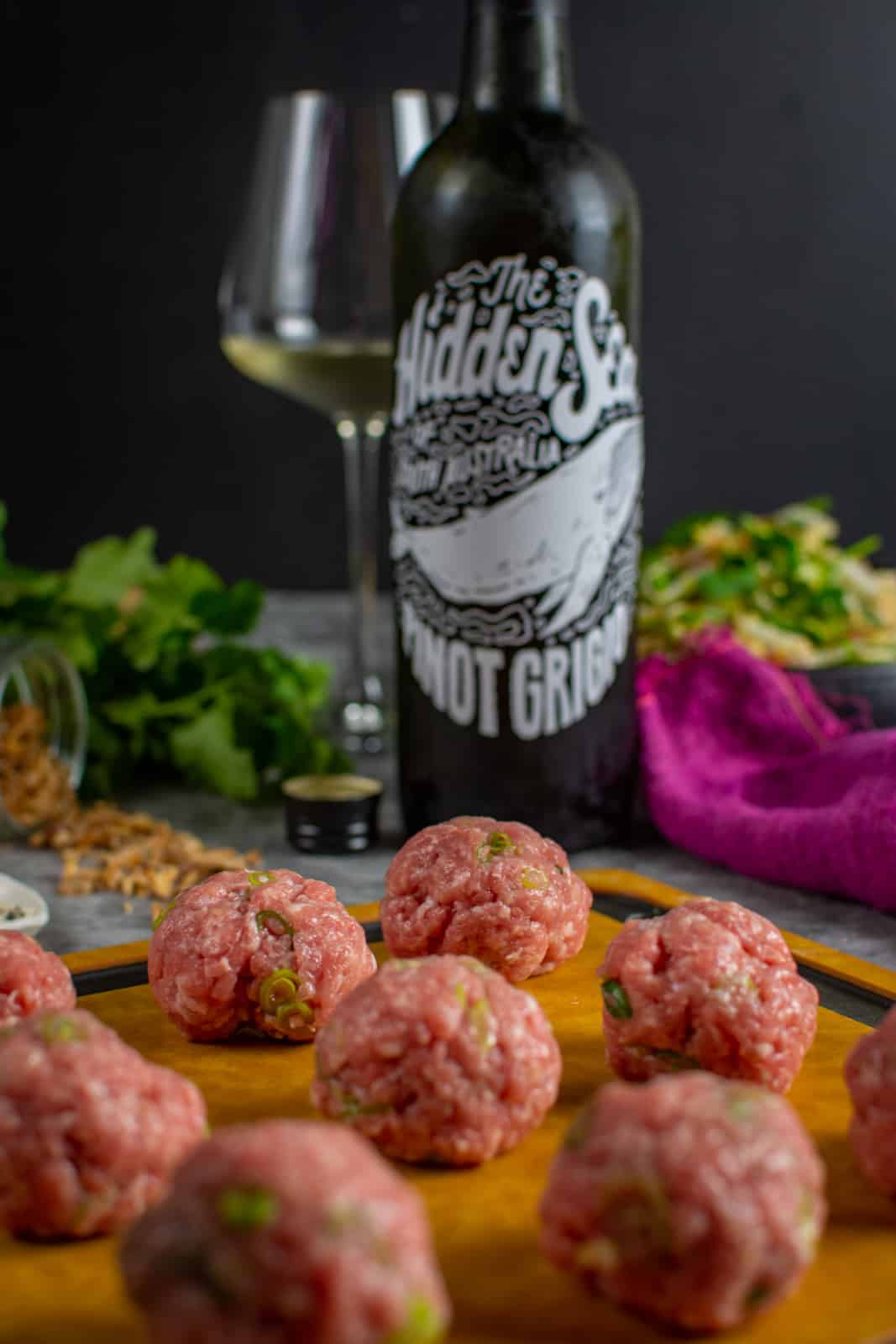 pork meatballs on chopping board, hidden sea pinot grigio behind