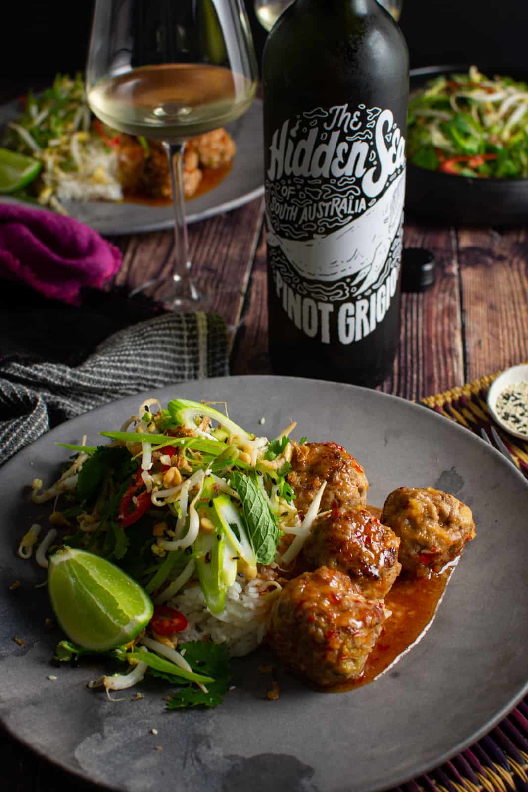 Asian pork meatballs on a plate, hidden sea pinot grigio behind