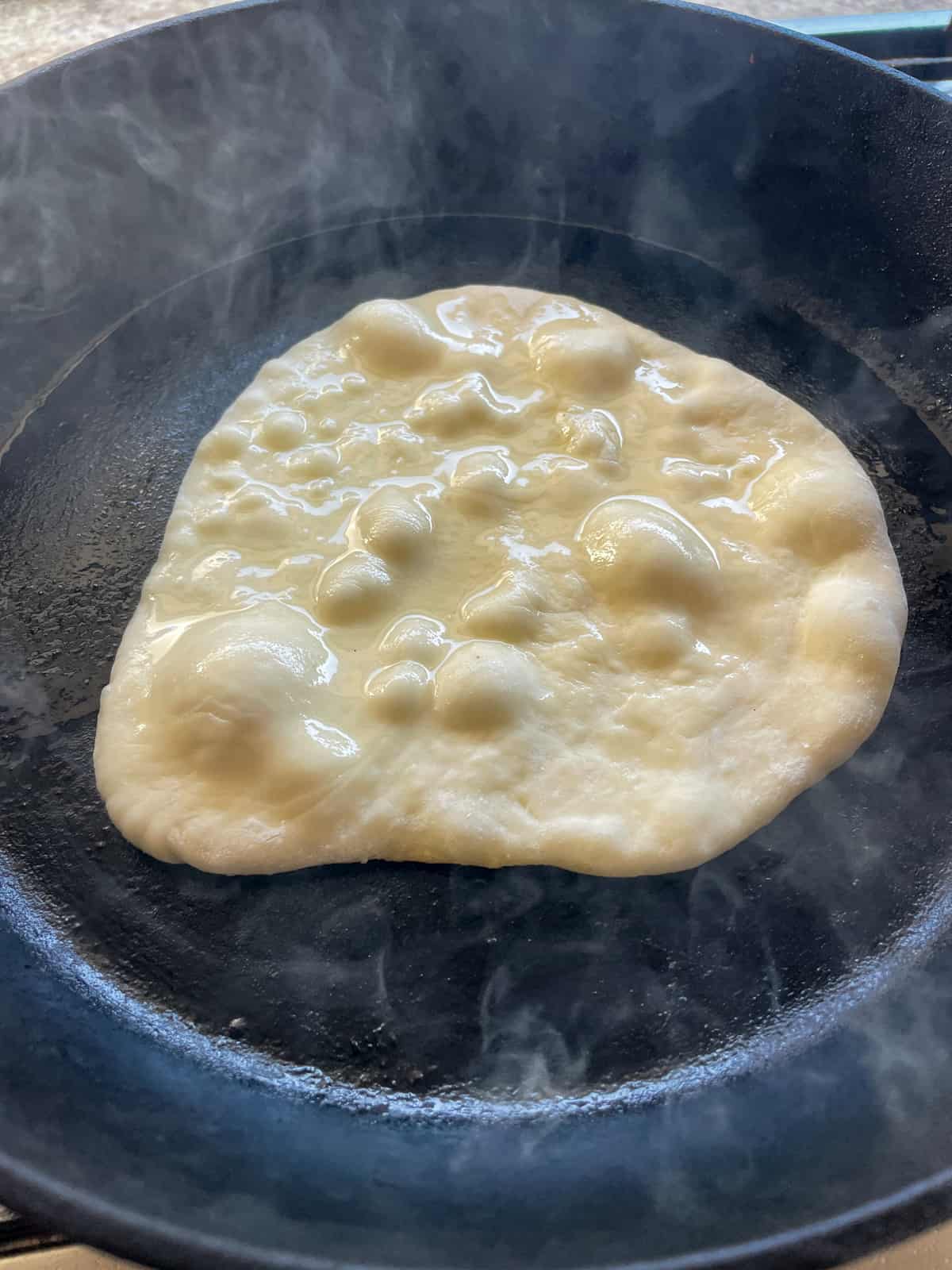 homemade pita cooking in cast iron pan