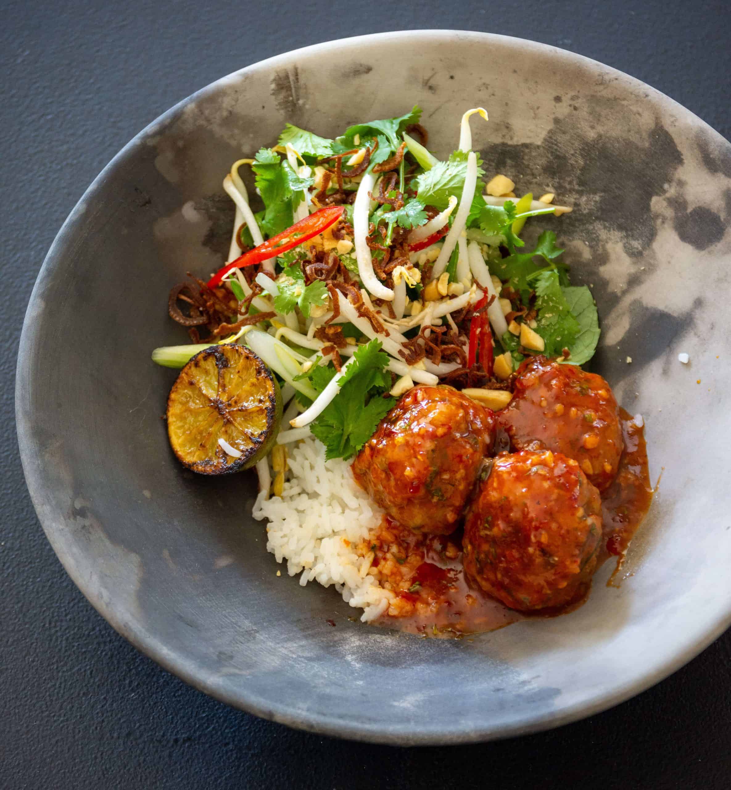 Asian pork meatballs in a bowl with rice and beansprout salad 
