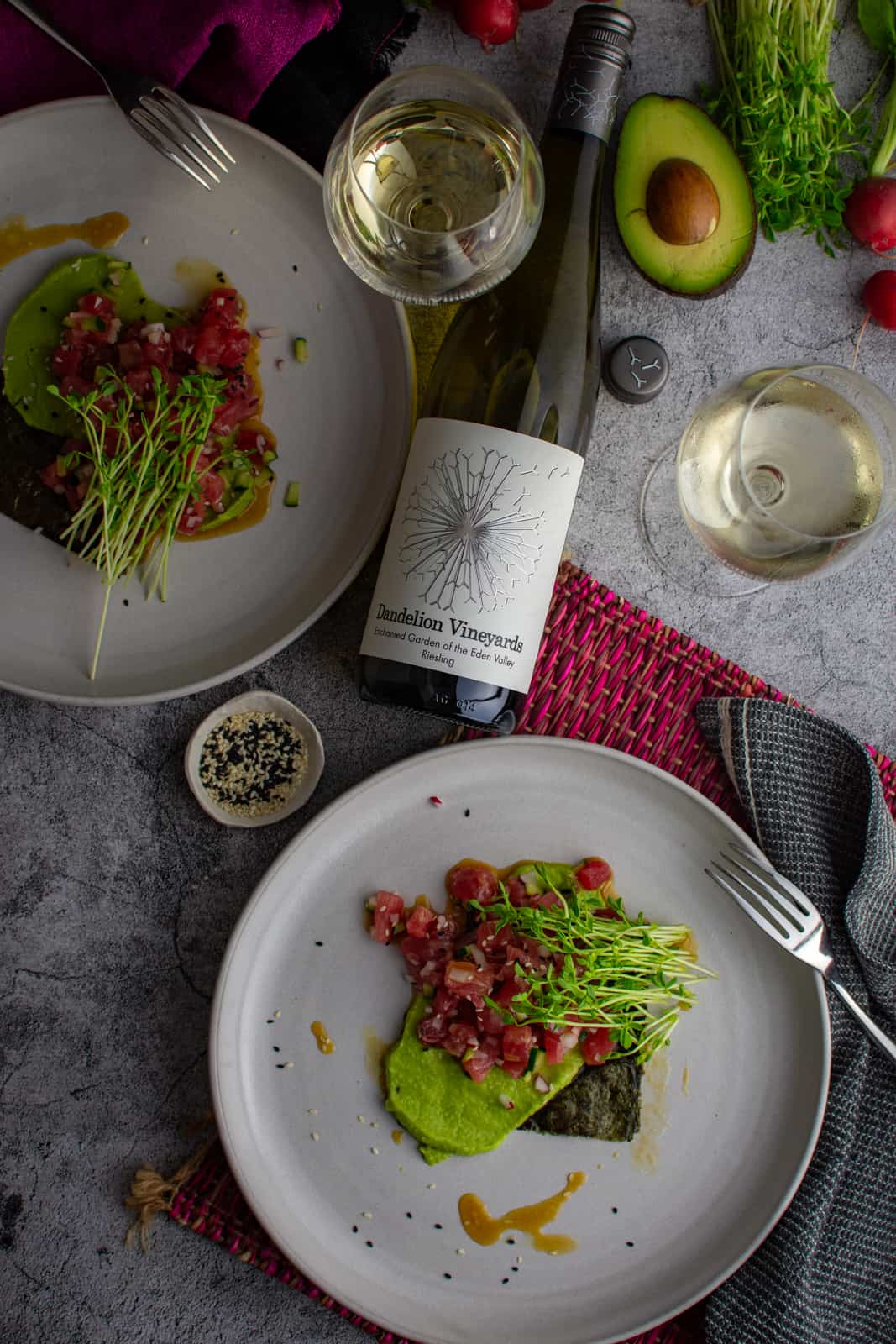 Tuna Crudo on a white plate, napkins, cutlery and dandelion riesling next to plates