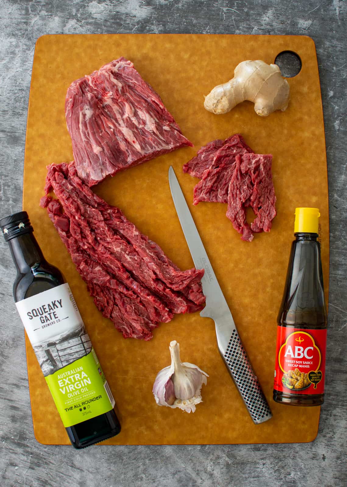sliced flap meat on a chopping board with marinade ingredients 