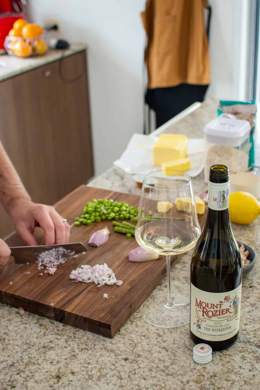 someone chopping shallots in a kitchen with other food on chopping board
