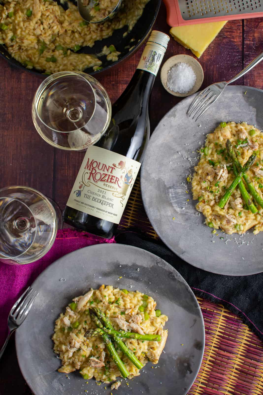 Two plates of crab risotto and Mount Rozier chenin blanc next to them on a table