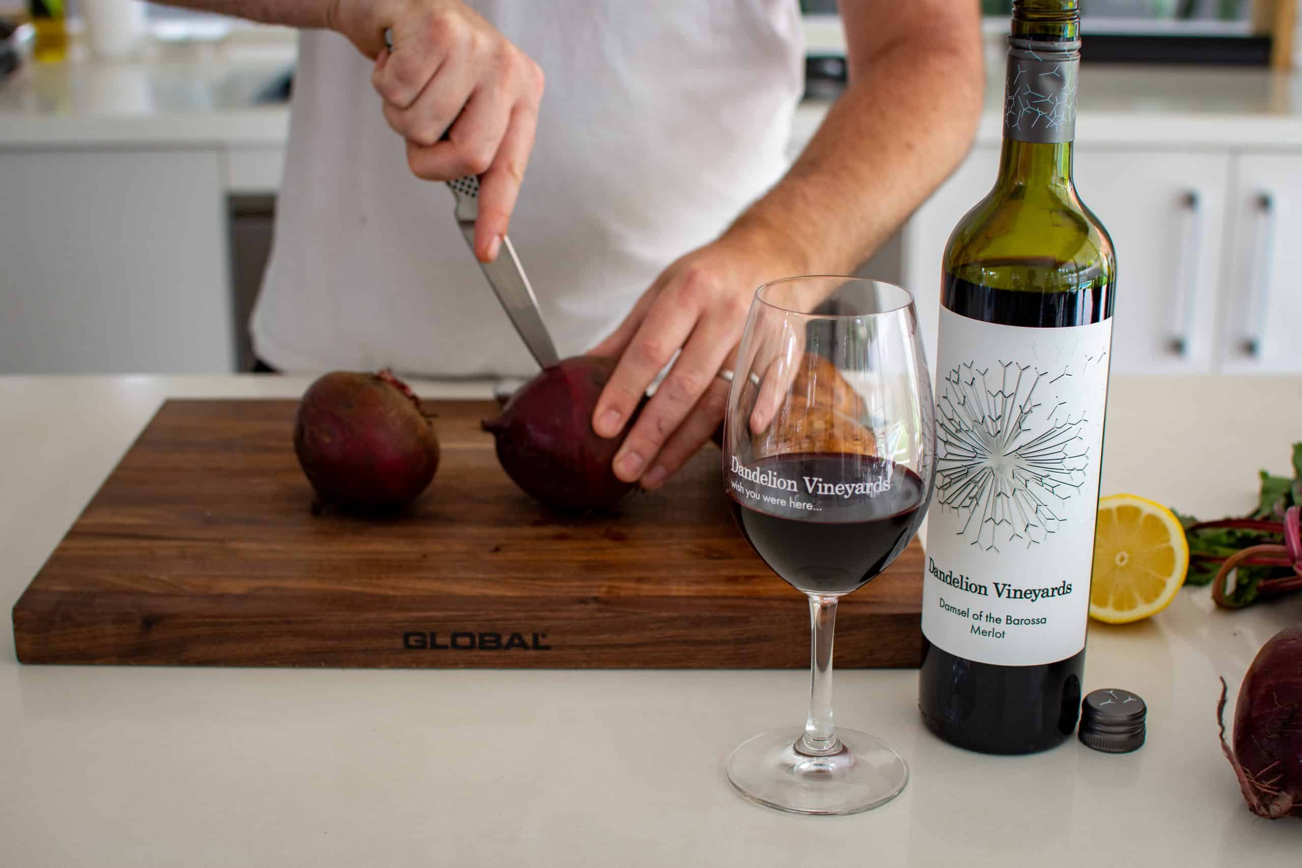 Dandelion vineyard wine with someone piercing a beetroot on a chopping board with a knife