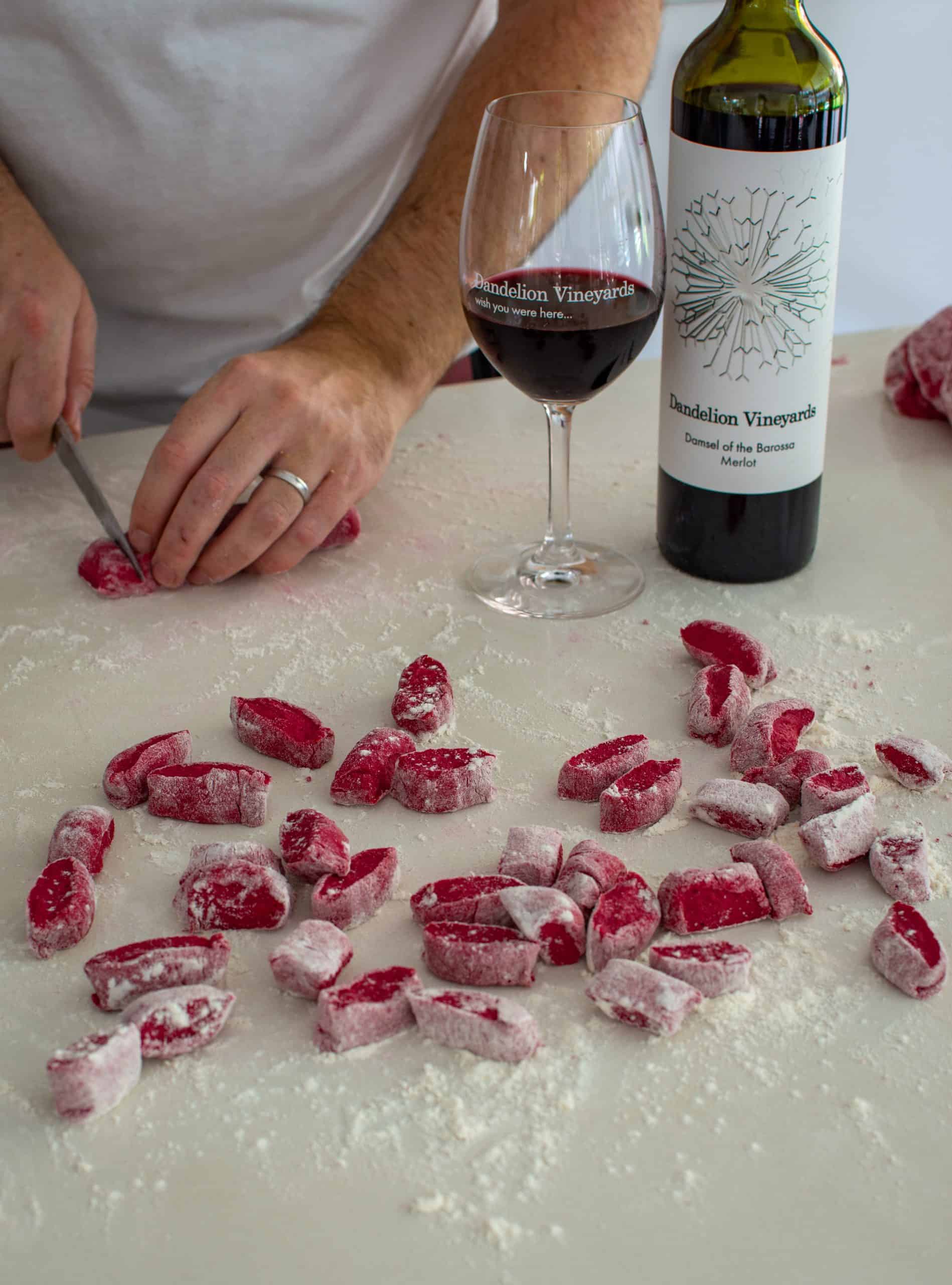 Someone cutting beetroot gnocchi on a kitchen countertop