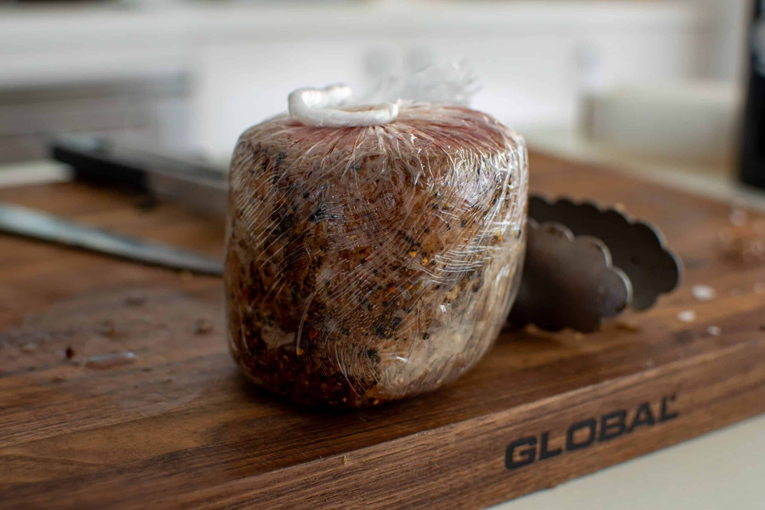 wrapped beef tenderloin on a chopping board