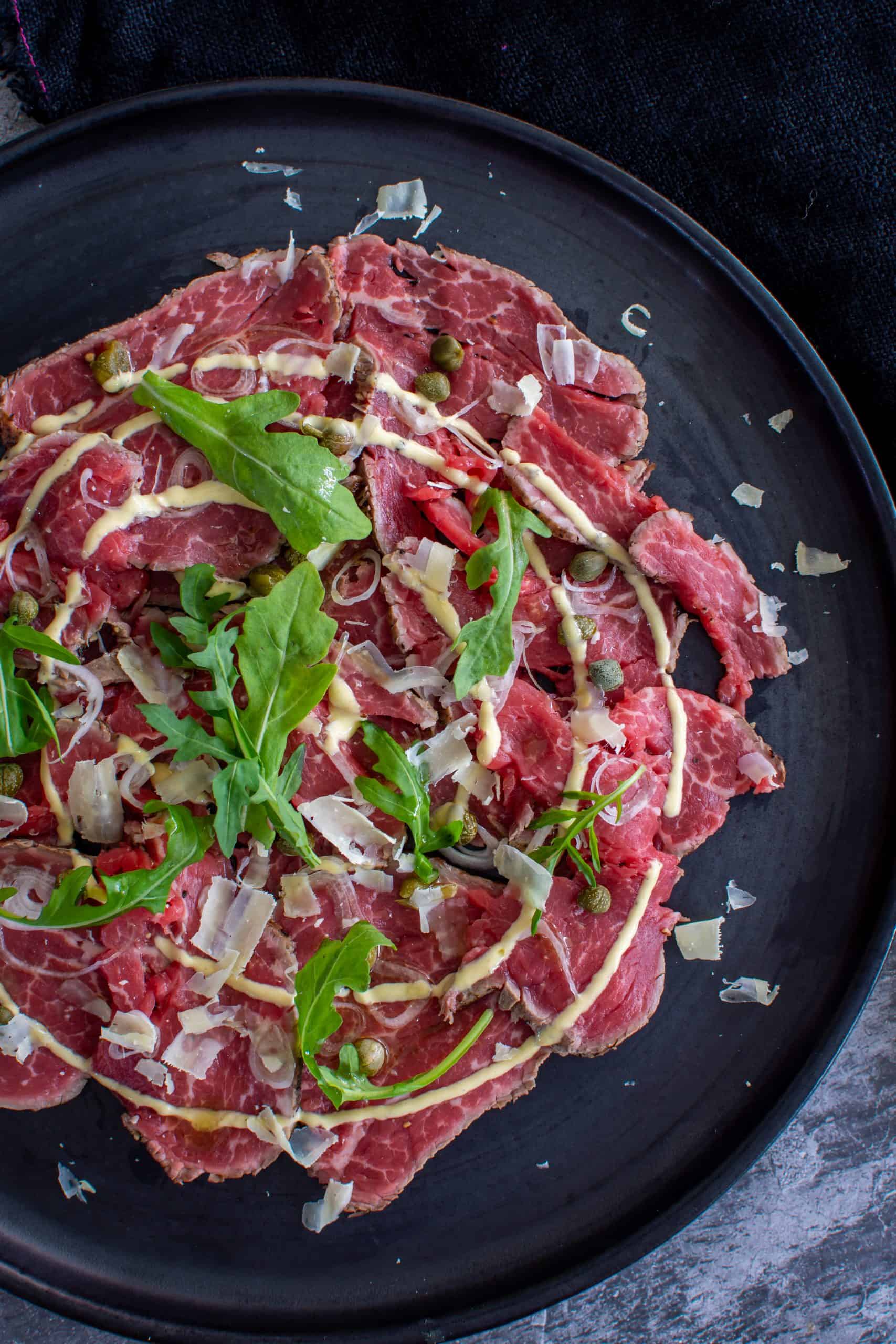 Birdseye view of beef carpaccio on a black plate