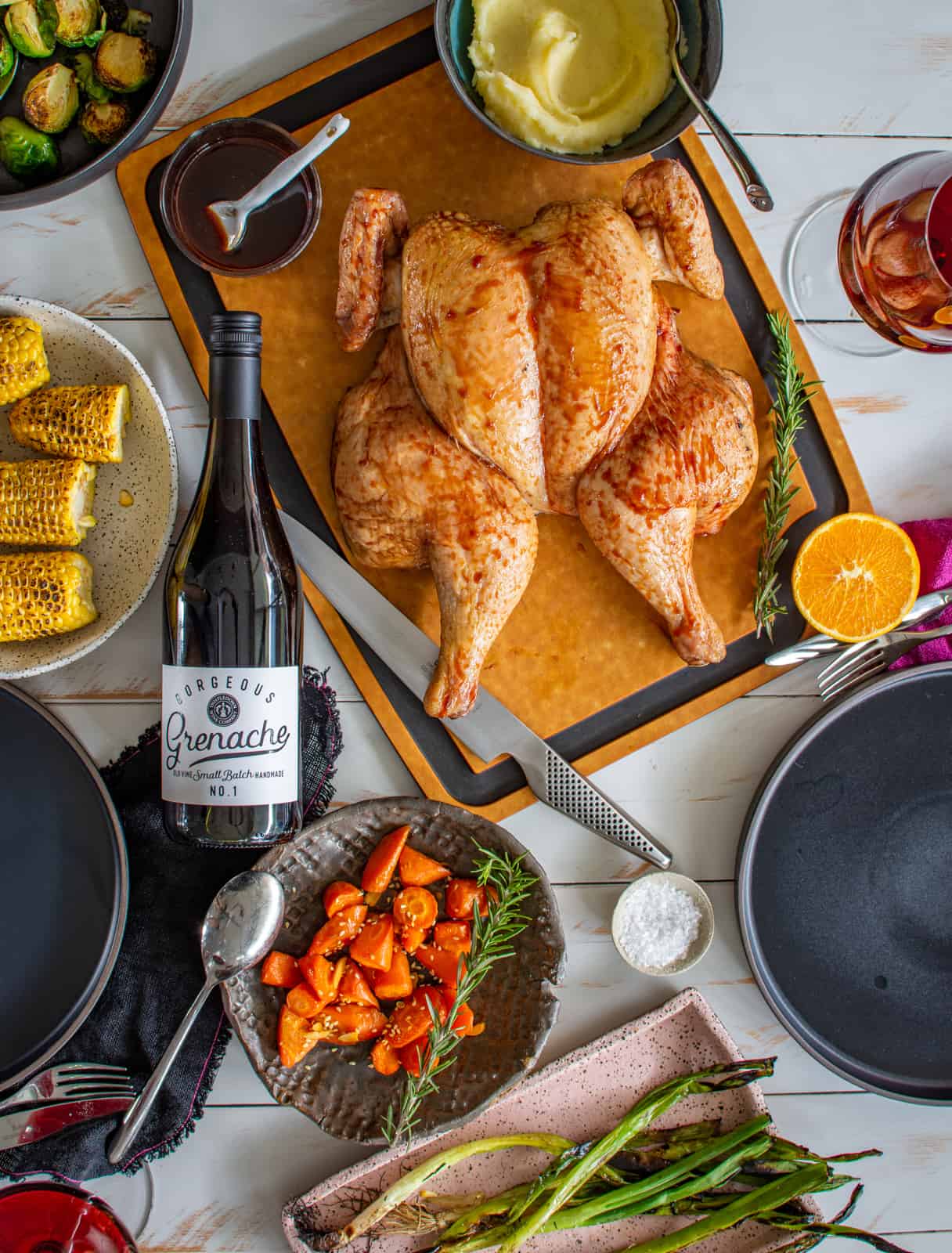 birdesye view of smoked spatchcock chicken with vegetables and wine on a table