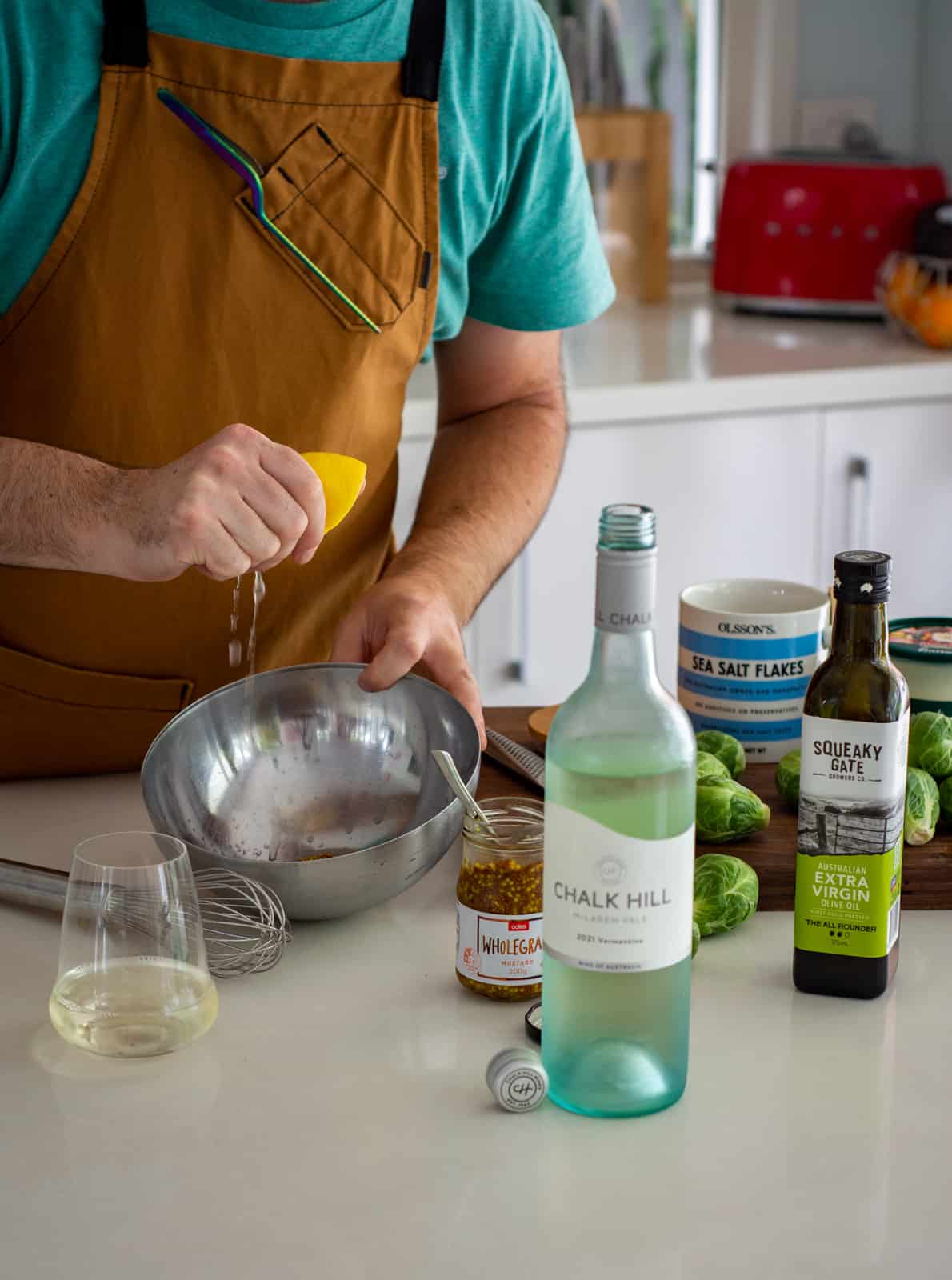 someone squeezing lemon into bowl in a kitchen with shaved brussels sprout salad ingredients on chopping board