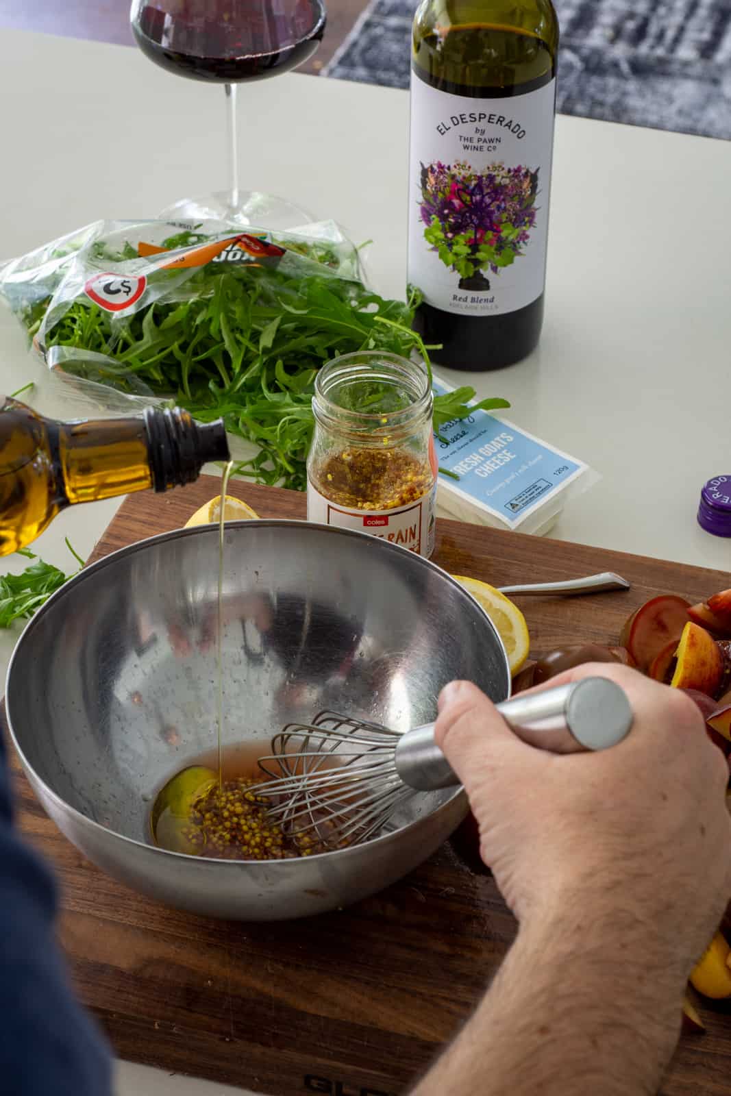 someone pouring olive oil into a bowl to make salad dressing