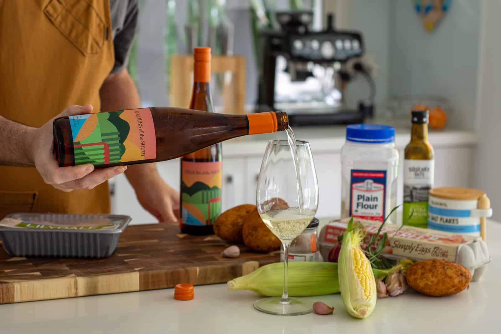 pouring a glass of wine in the kitchen with gnocchi ingredients on counter top