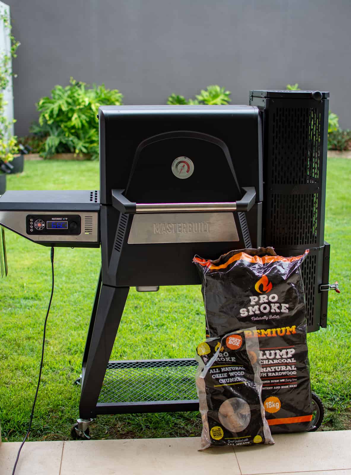 Masterbuilt BBQ in garden with charcoal next to it