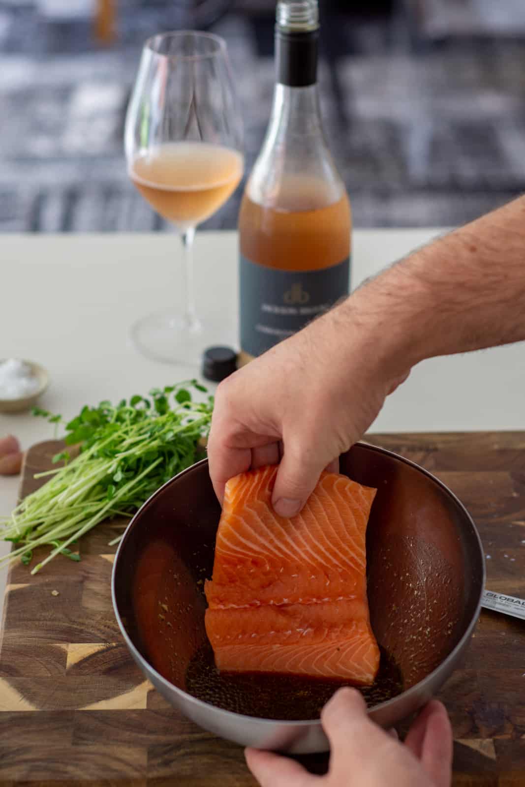 placing a piece of salmon into teriyaki marinade