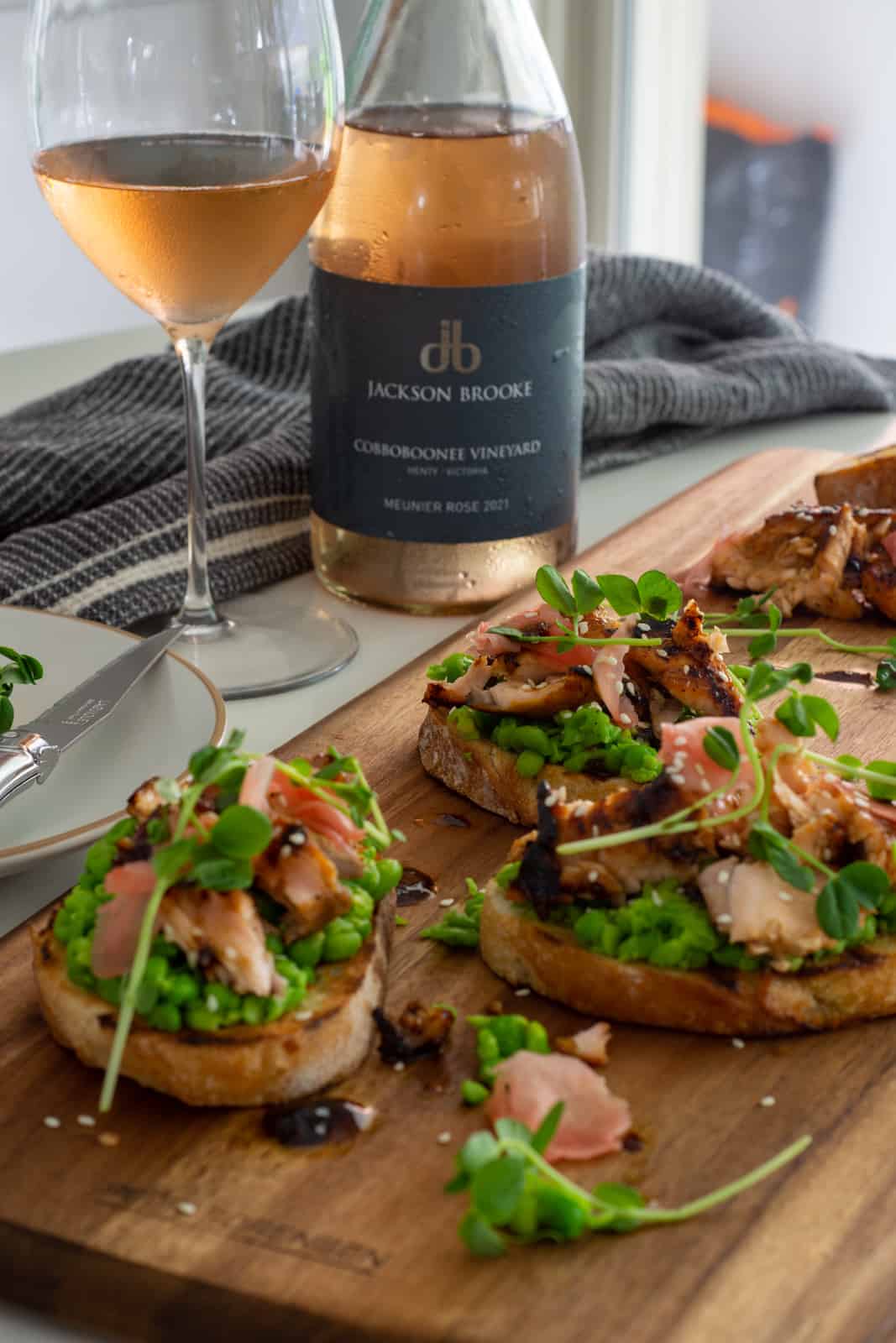 pan-fried teriyaki salmon toast on wooden board with rose wine beside