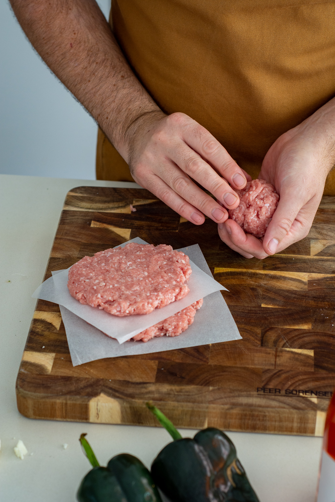 someone forming pork burger patties on a chopping board