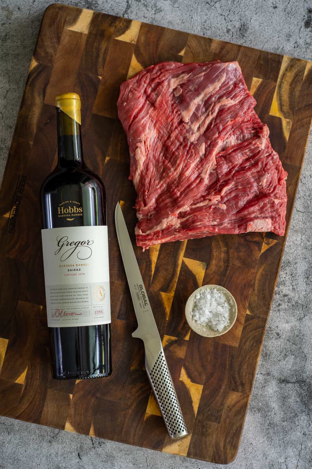 flap steak, boning knife and red wine on a chopping board