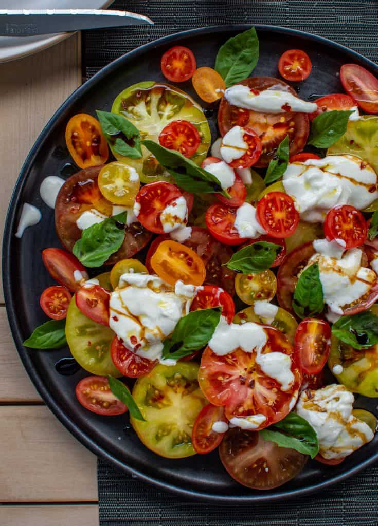 Delicious tomato & burrata salad on a black plate