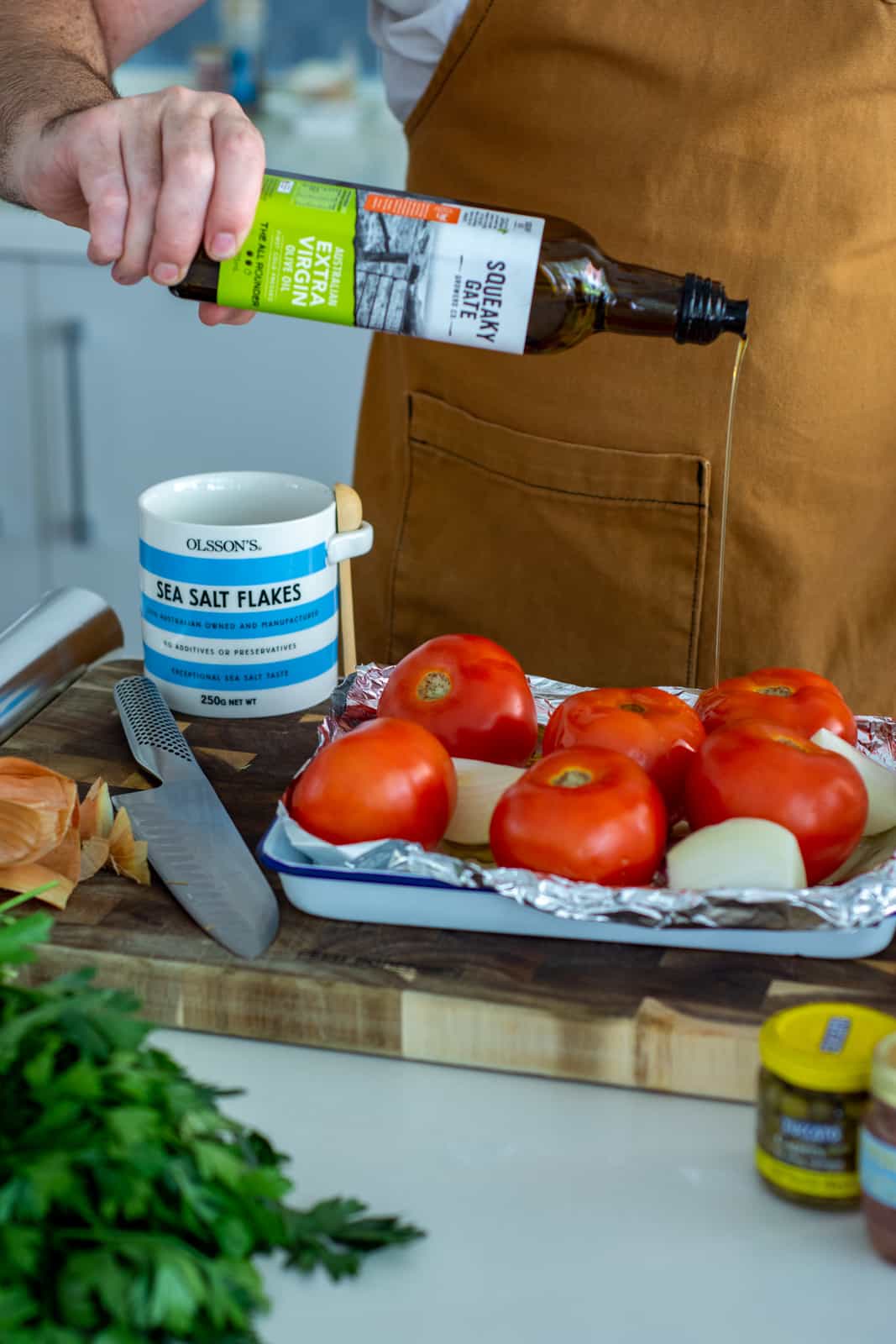 someone drizzling olive oil over tomatoes