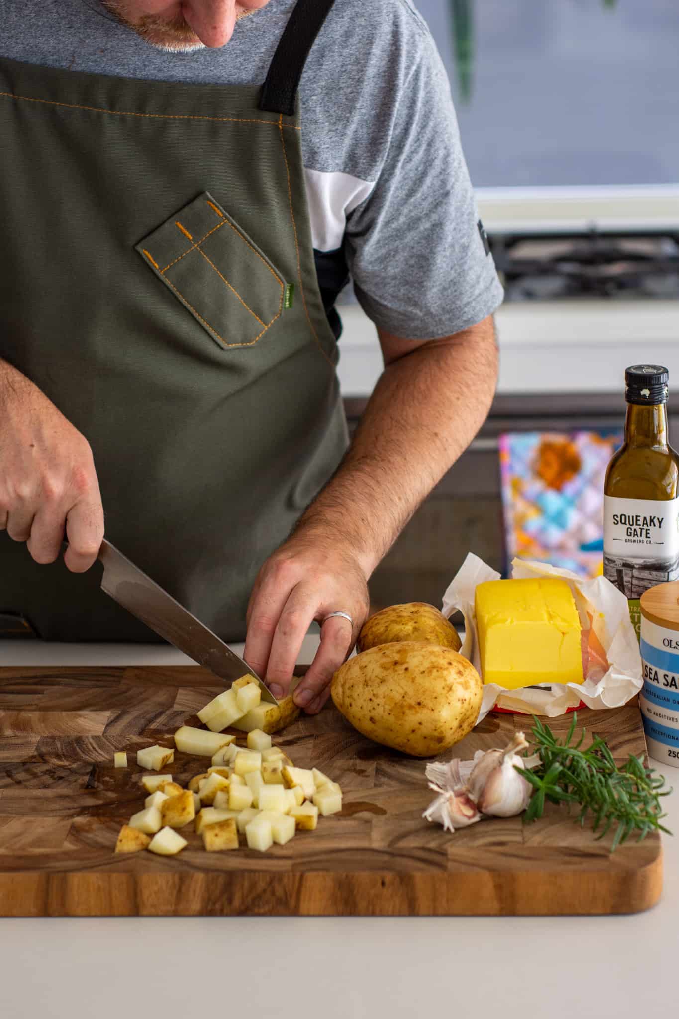 someone chopping potatoes in the kicthen with other ingredients around them on counter