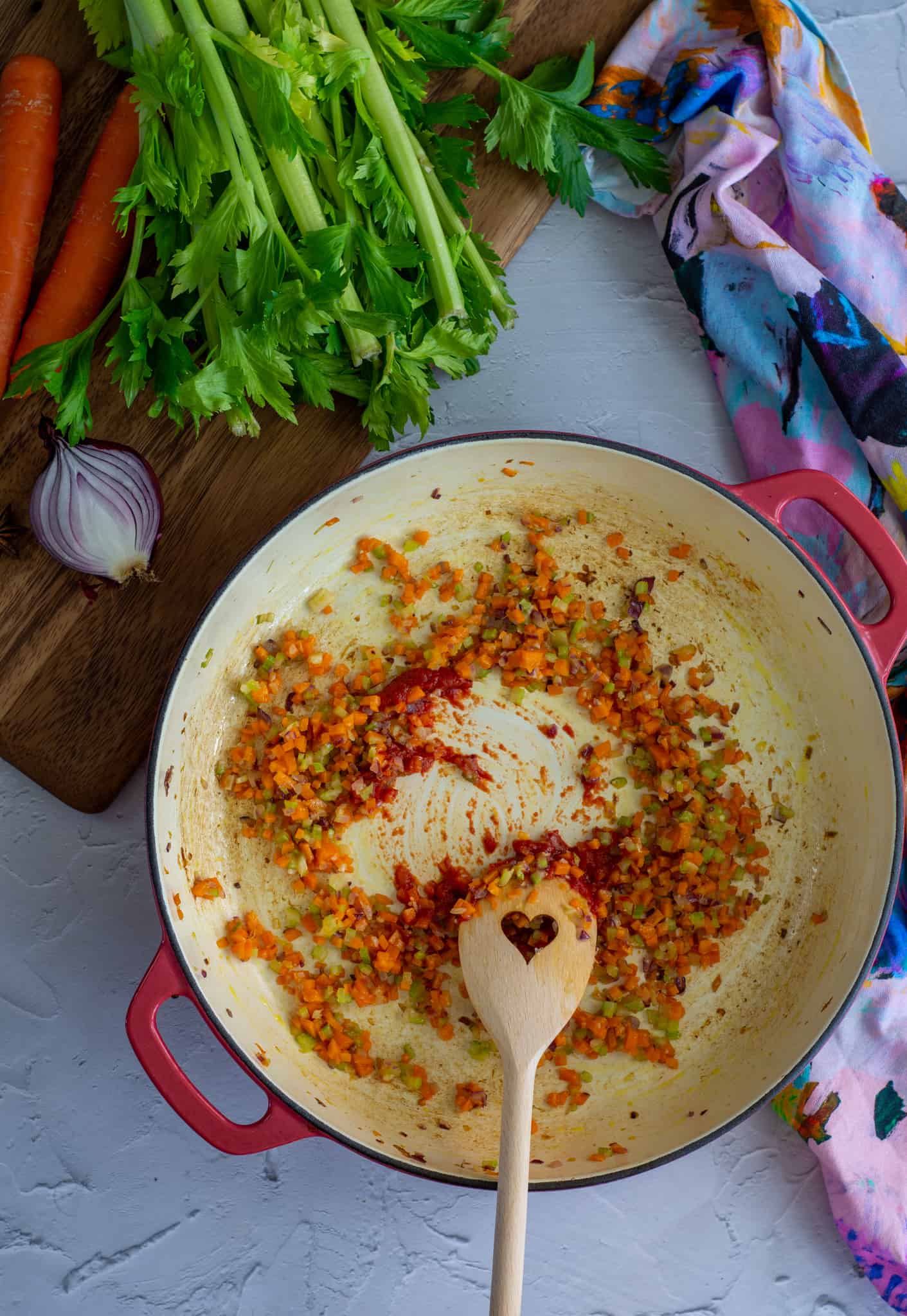 Tomato paste being stirred into hot pan with vegetables