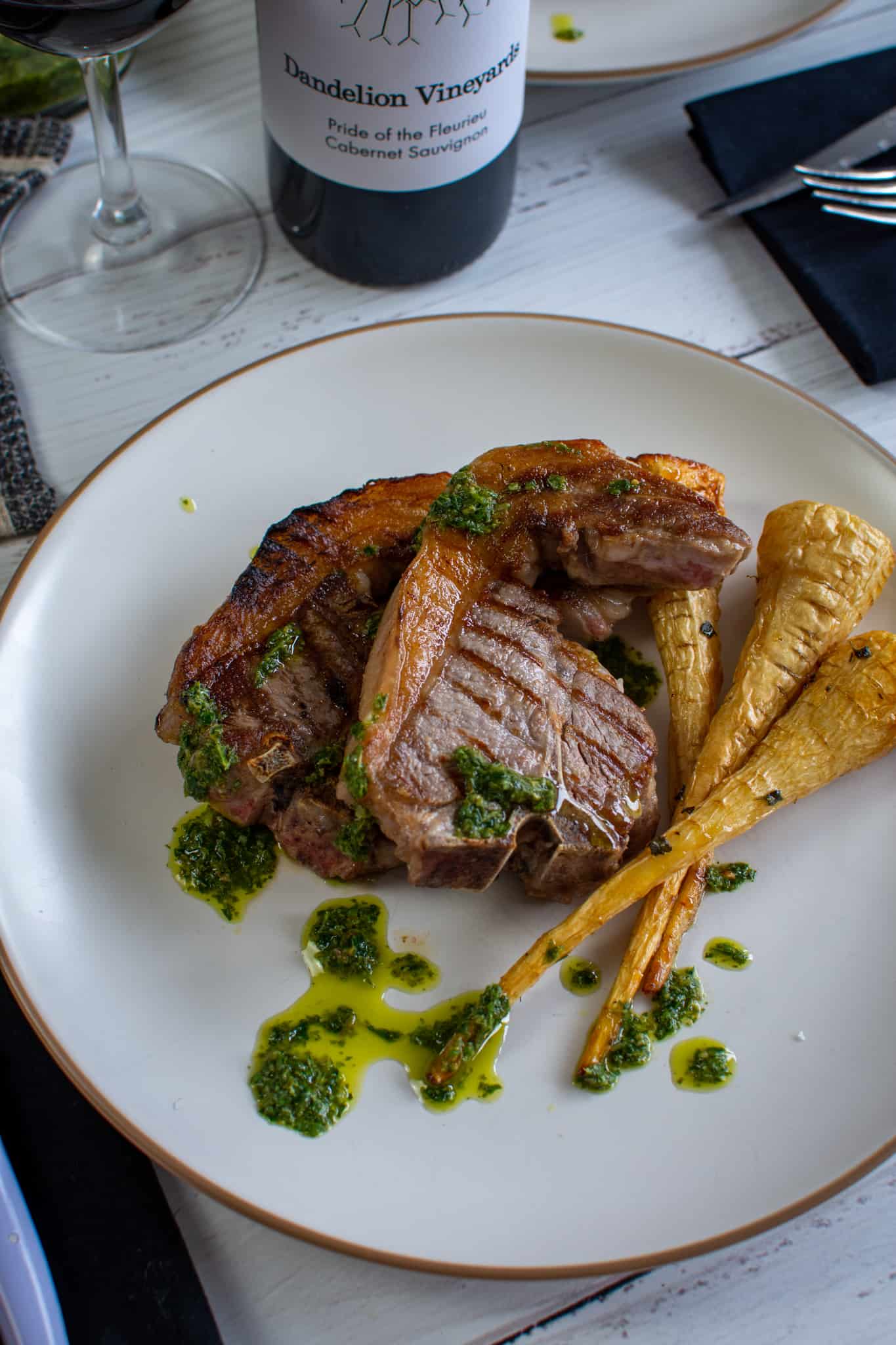 grilled lamb loin chops on a plate with salsa verde and parsnips