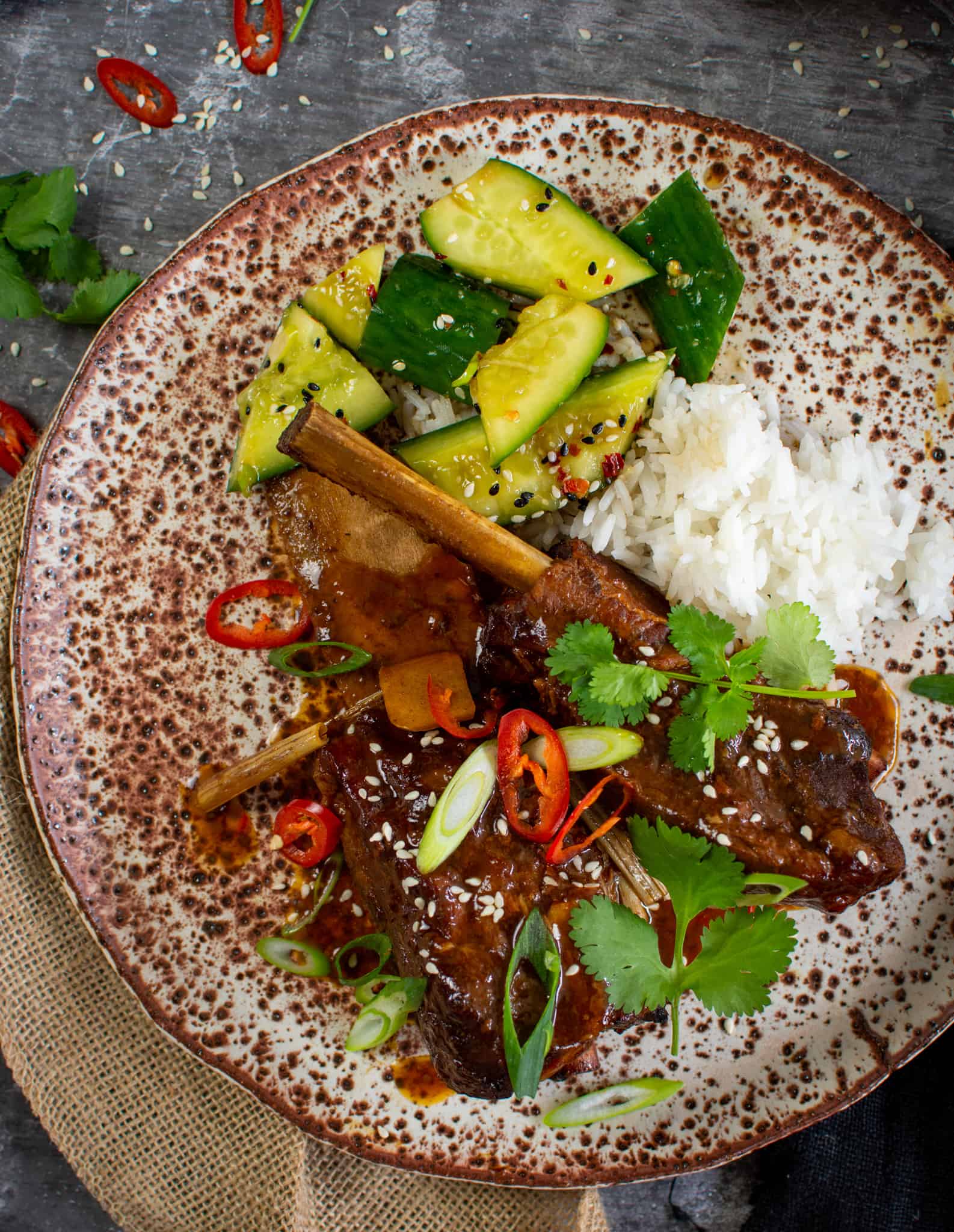 Asian slow-cooked beef short ribs, cucumber salad and rice on a plate