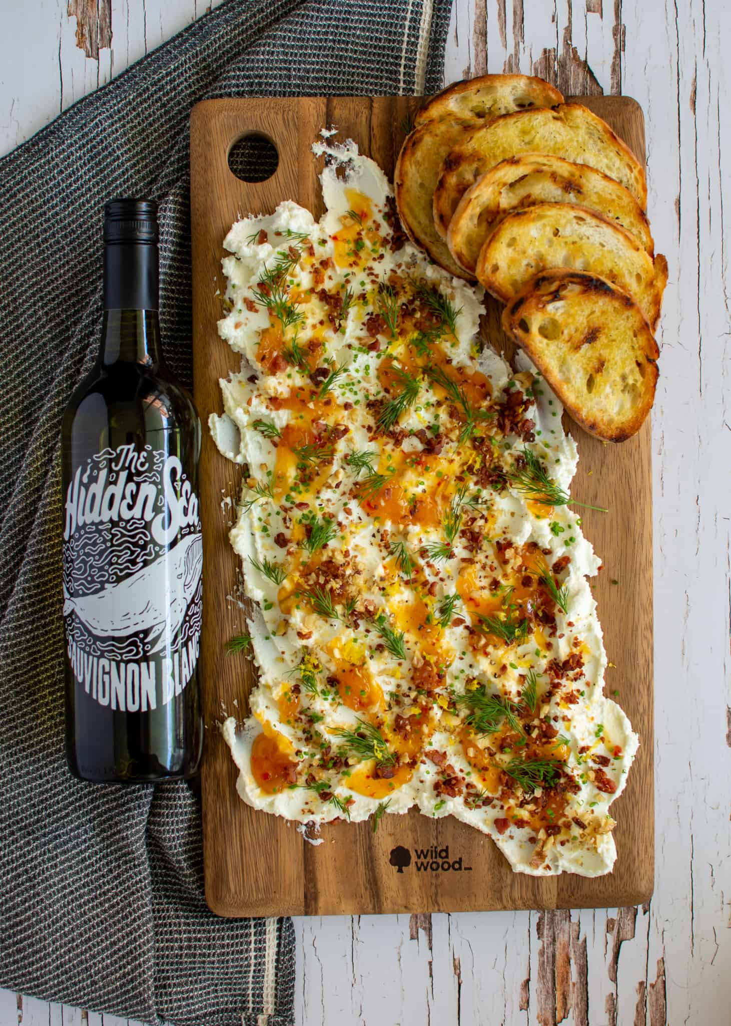 birdseye view of goats cheese butter board and a bottle of hidden sea sauvignon blanc