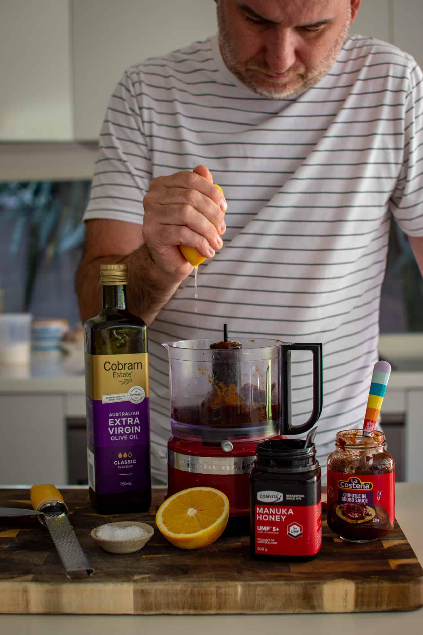 Someone squeezing an orange into a blender to make chipotle orange sauce