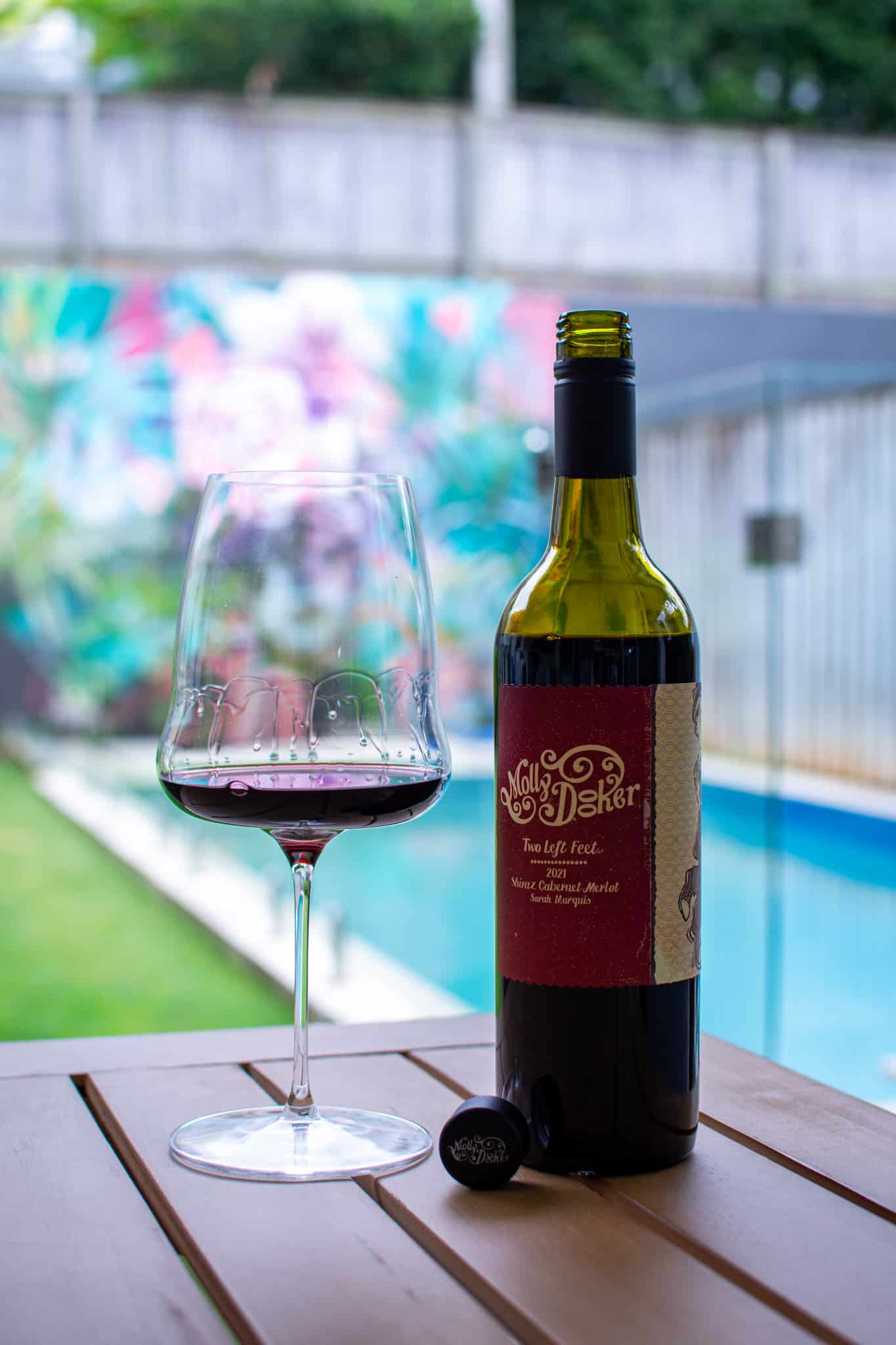 bottle of mollydooker wine with a wine glass next to it on an outdoor table