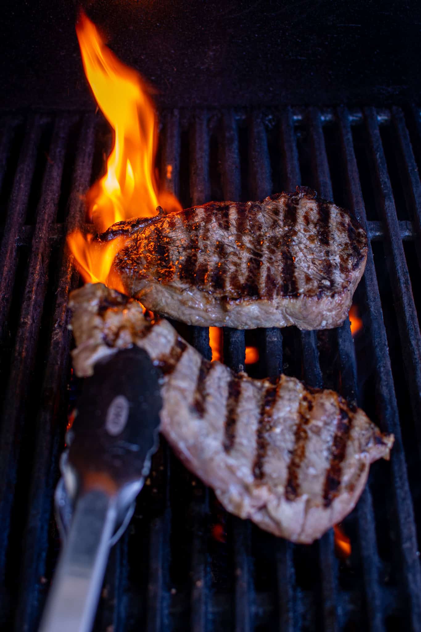 steaks on a bbq with a flame