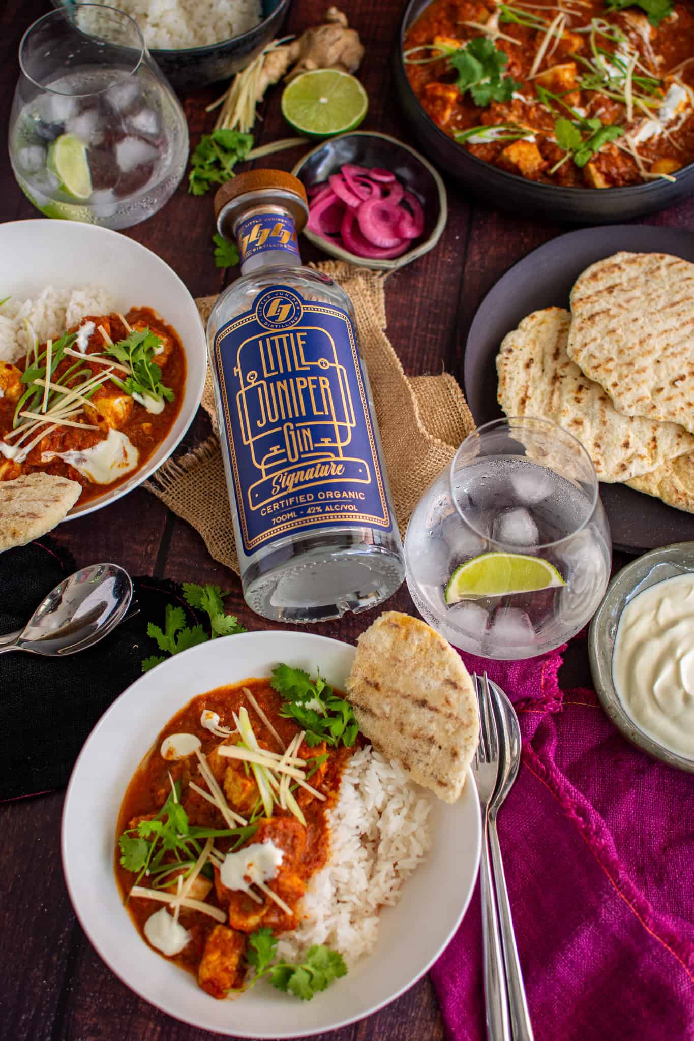 bowls of swordfish curry with flatbreads, pickled onions and gin beside them